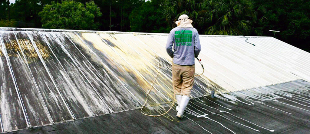 A homeowner cleaning their roof with a pressure washer and mild soap